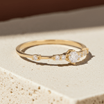 Gold ring with cubic zirconias on a beige stone surface
