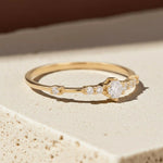 dainty Gold ring with cubic zirconias on a beige stone surface