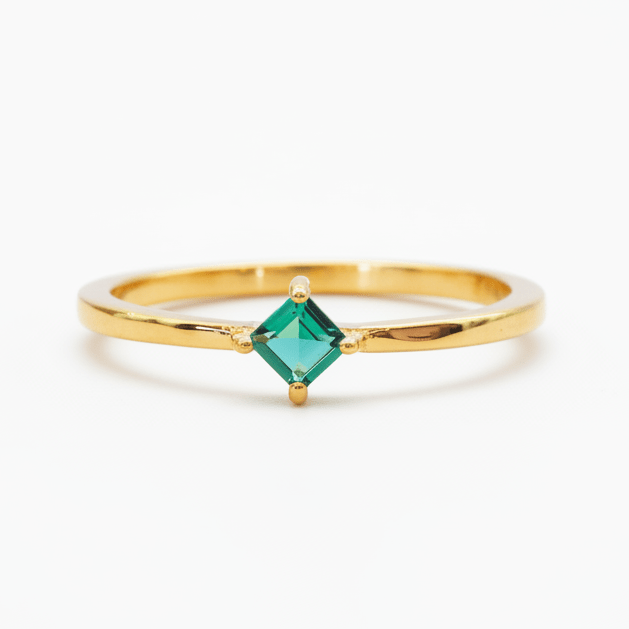 Gold ring with a green gemstone on a white background