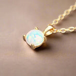 Gold necklace with an opal pendant on a beige background