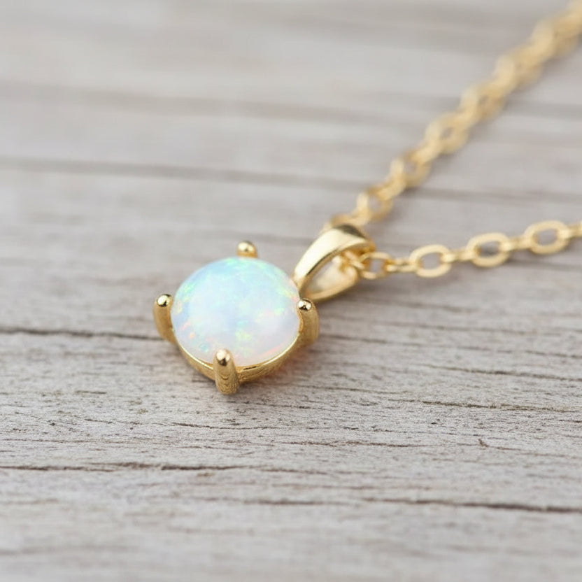 Gold necklace with an opal pendant on a beige background