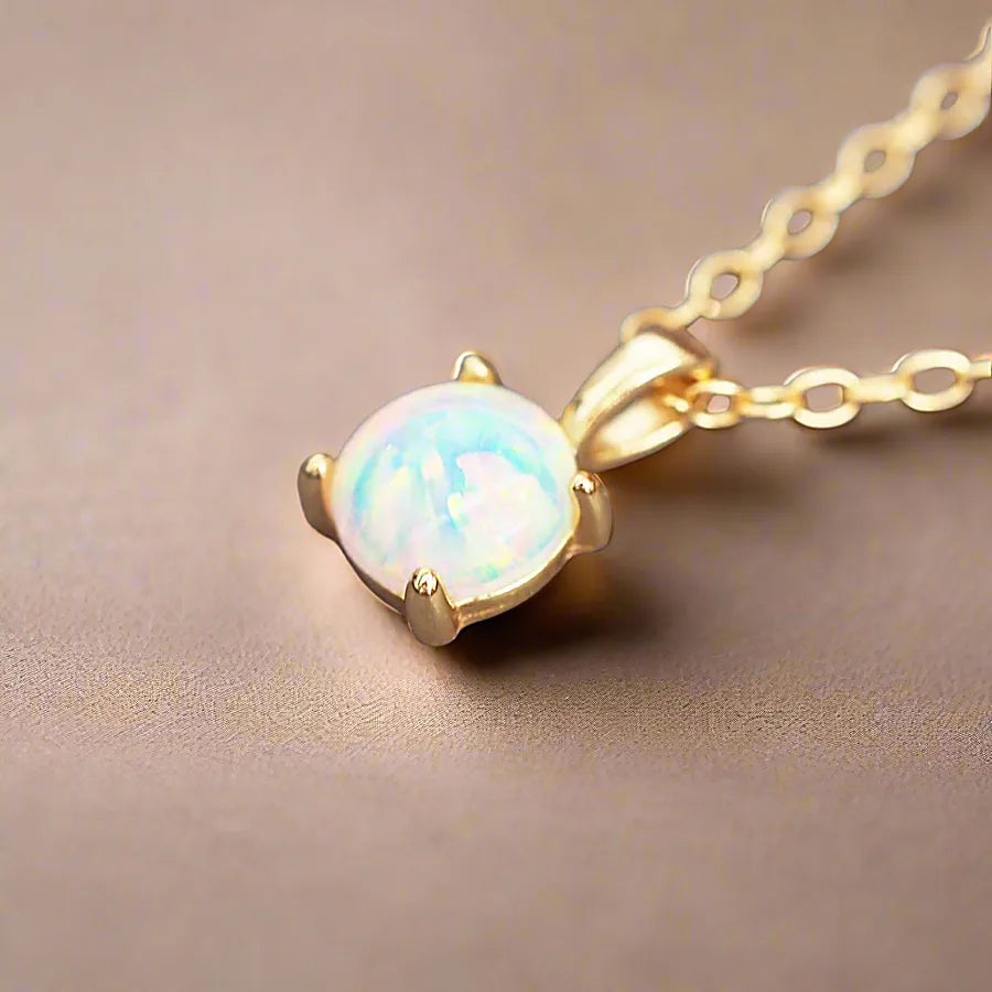 Gold necklace with an opal pendant on a beige background