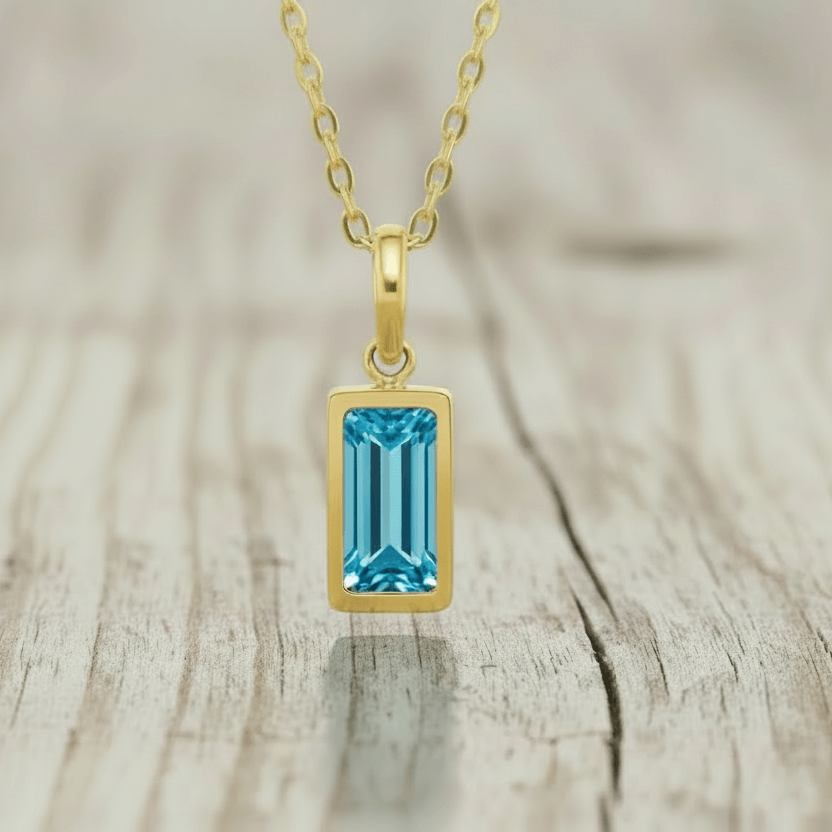 Gold necklace with a blue gemstone pendant on a white background