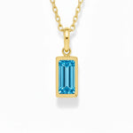 gold december birthstone necklace with blue cubic zirconia on a white background.
