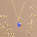 Birthstone necklace by Indie and Harper featuring a purple teardrop tanzanite pendant on a gold chain