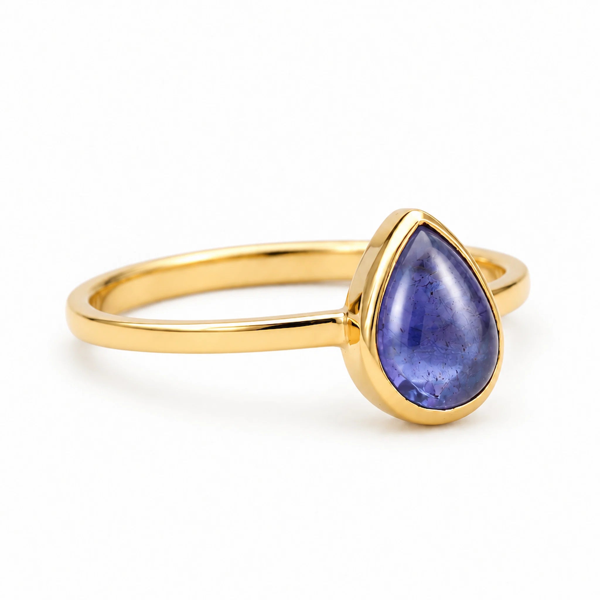 Gold December Birthstone ring with a teardrop-shaped natural tanzanite gemstone on a light background
