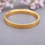 Gold ring on a gray surface with blurred floral background
