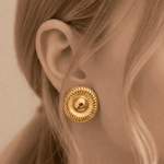 Gold earring worn by a person with blonde hair.