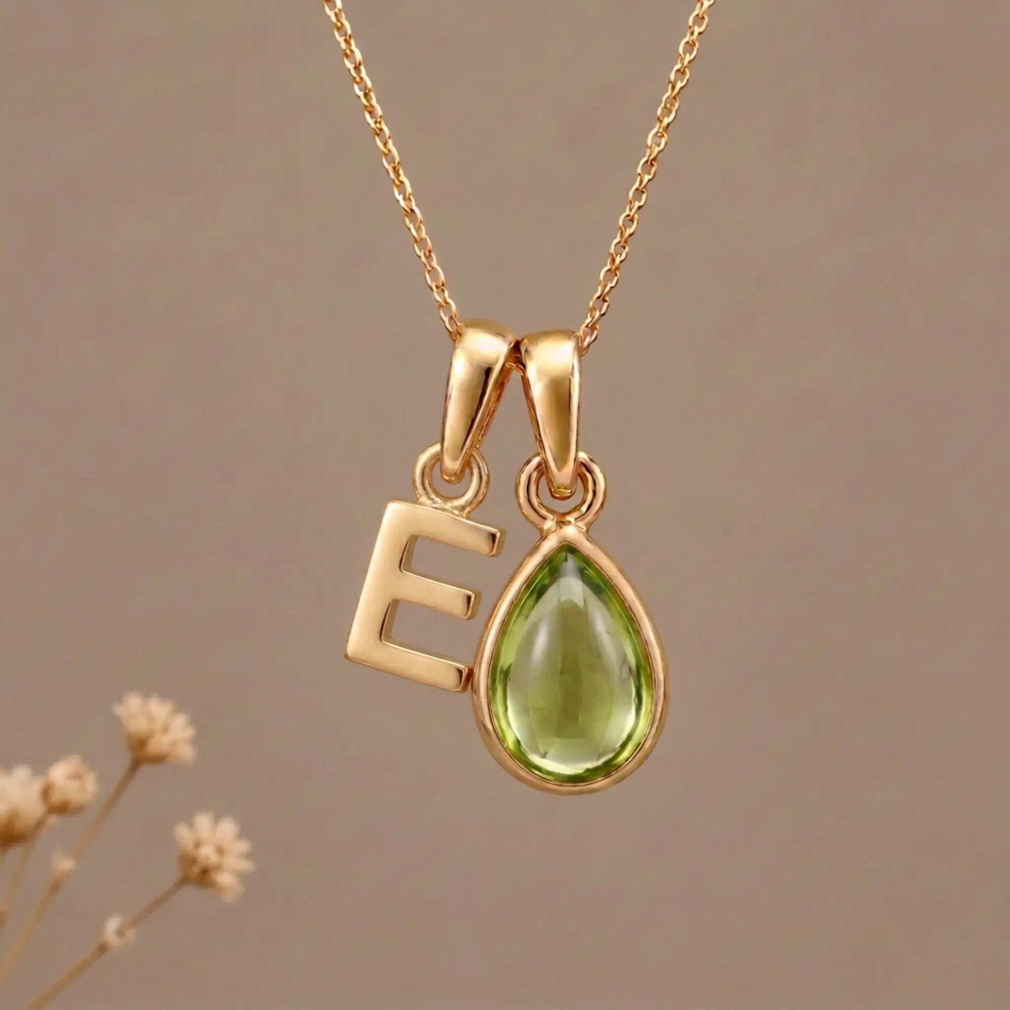 Gold Initial E Pendant and August birthstone Natural Peridot Necklace against a warm background