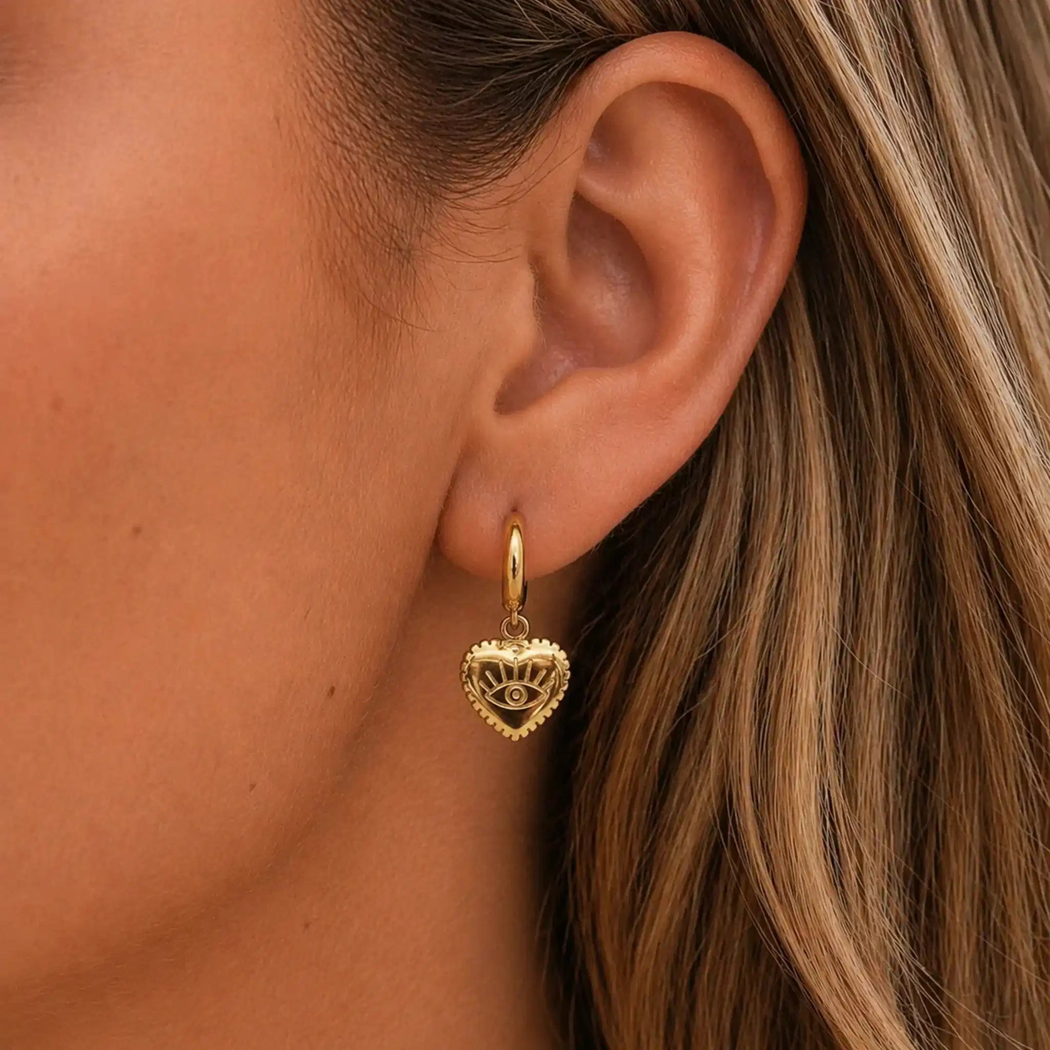 Close-up of a person wearing a gold heart-shaped earring.