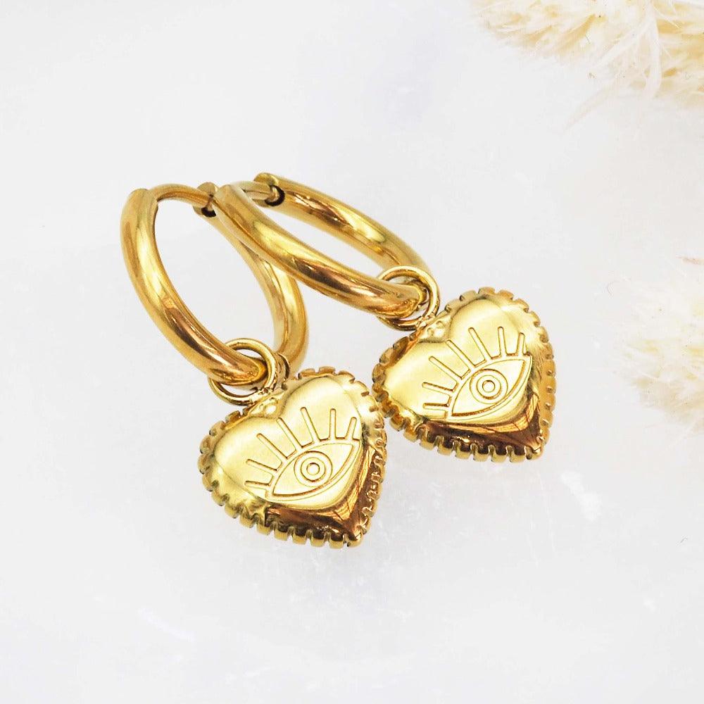 waterproof stainless steel gold evil eye heart charm huggie earrings on a white background