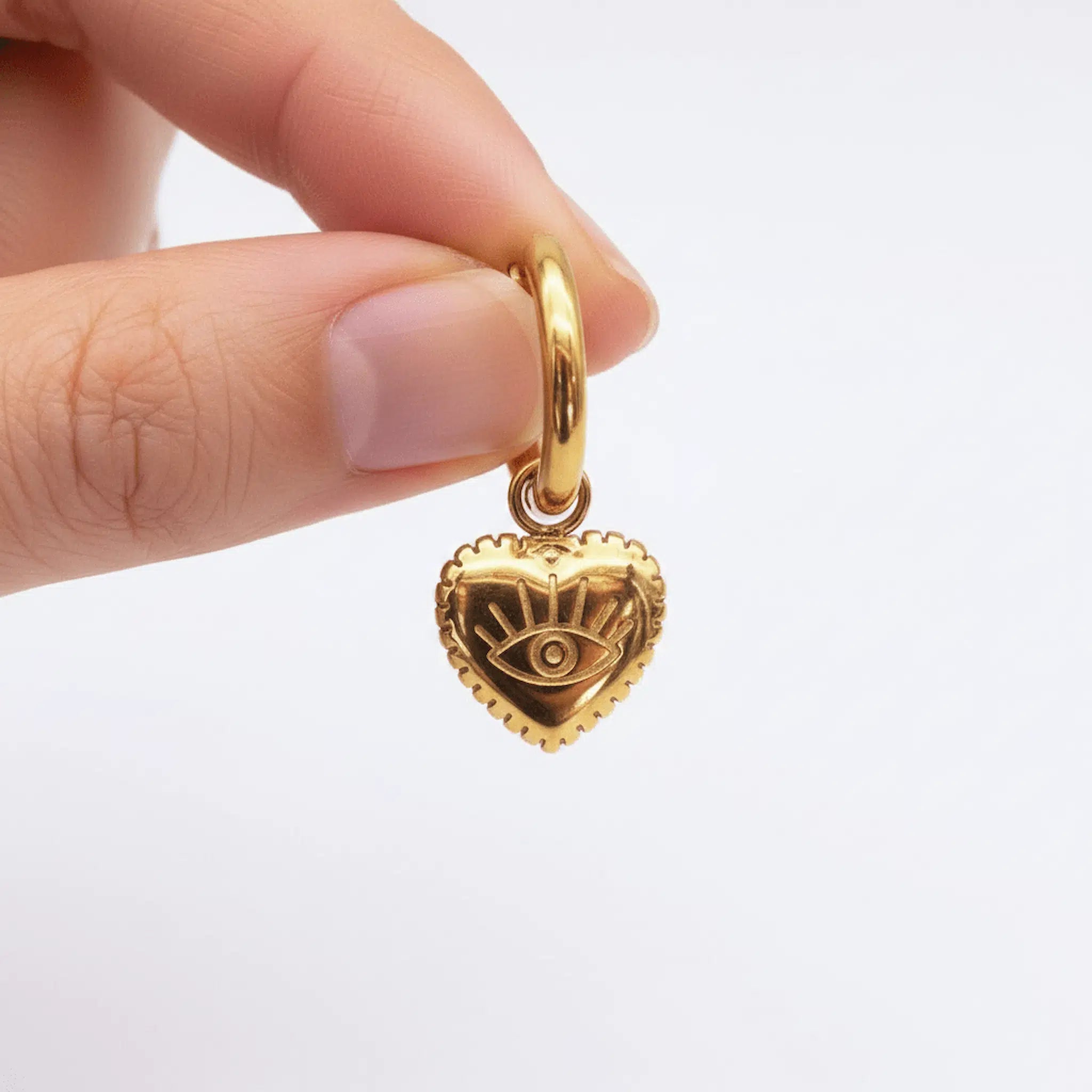 waterproof stainless steel gold evil eye heart charm huggie earring being held