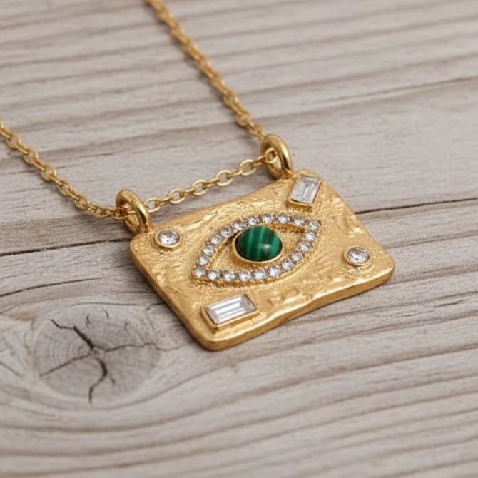 Close-up of gold Evil Eye necklace featuring a round malachite stone and sparkling cubic zirconia details on a textured pendant.