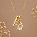 Gold initial F necklace with an April clear quartz teardrop on brown with dried flowers