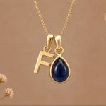 Gold Initial F Pendant and September birthstone Natural Sapphire Necklace against a warm background
