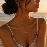 Woman on a beach with a gold double pendant necklace including a letter A pendant and a february birthstone amethyst pendant