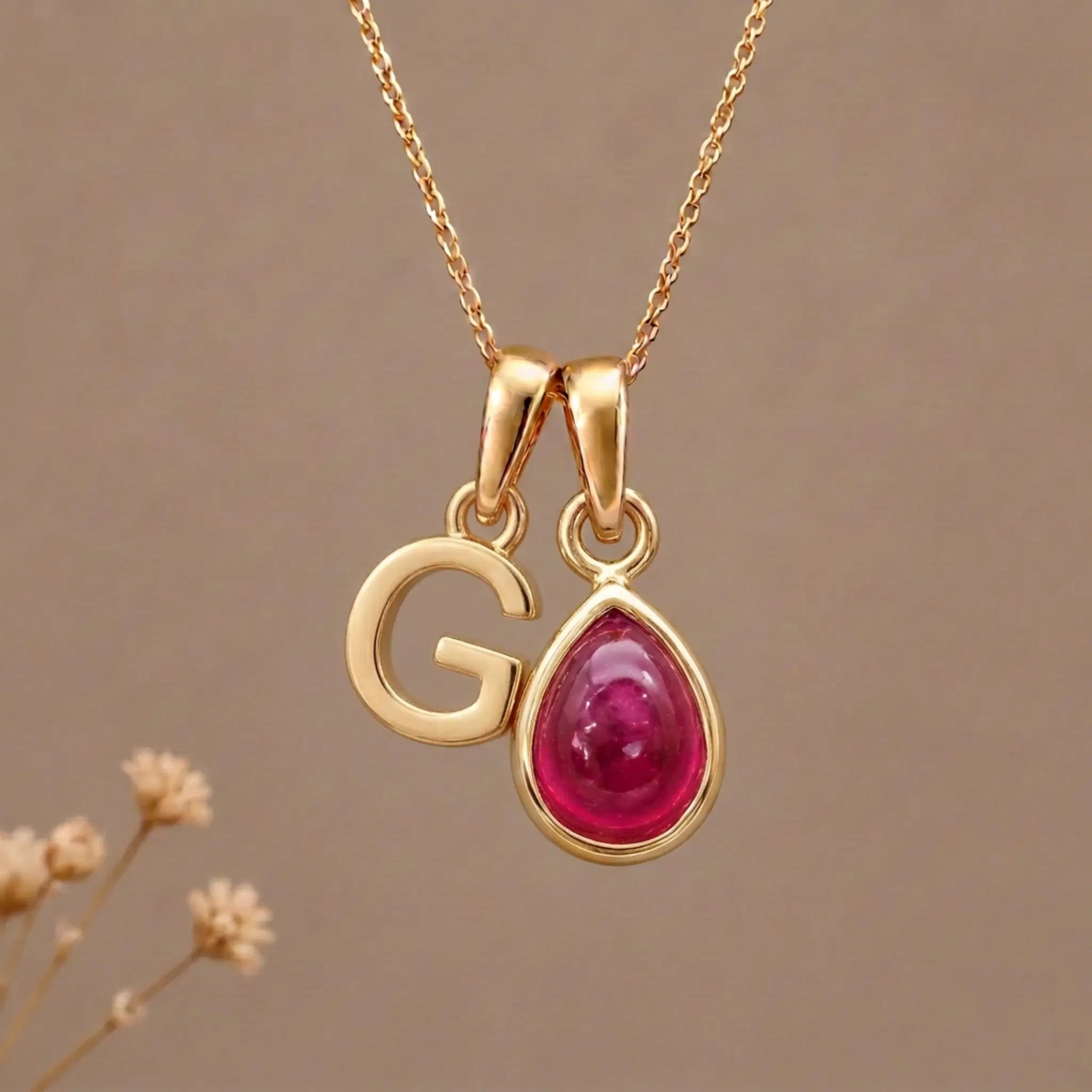 Gold Initial G Pendant and July birthstone Natural Ruby Necklace against a warm background