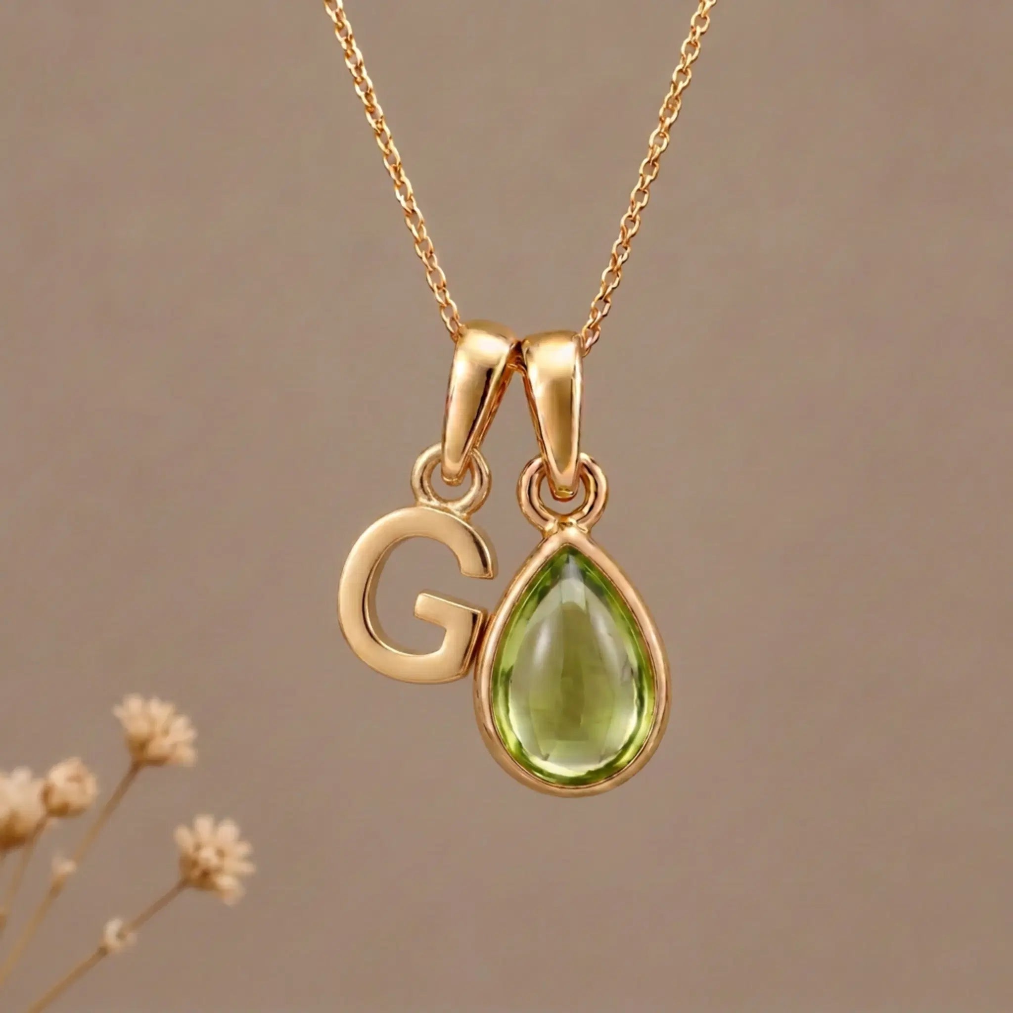 Gold Initial G Pendant and August birthstone Natural Peridot Necklace against a warm background