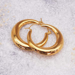 Gold hoop earrings on a textured white surface