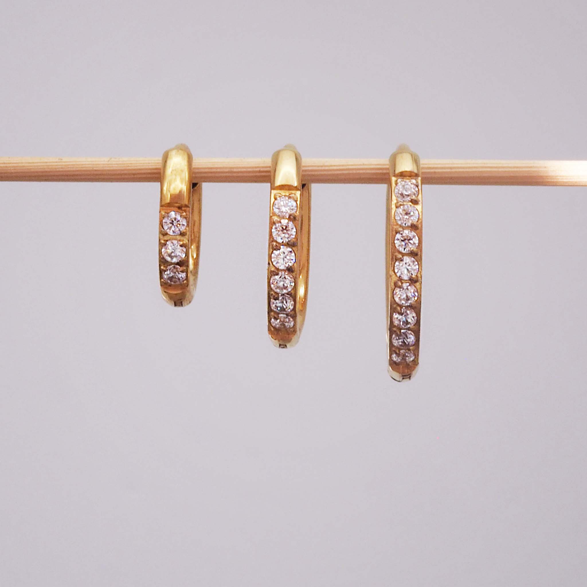 Three waterproof pavé gold hoop earrings in three different hoop and huggie earring sizes