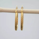 Gold hoop earrings on a light grey background