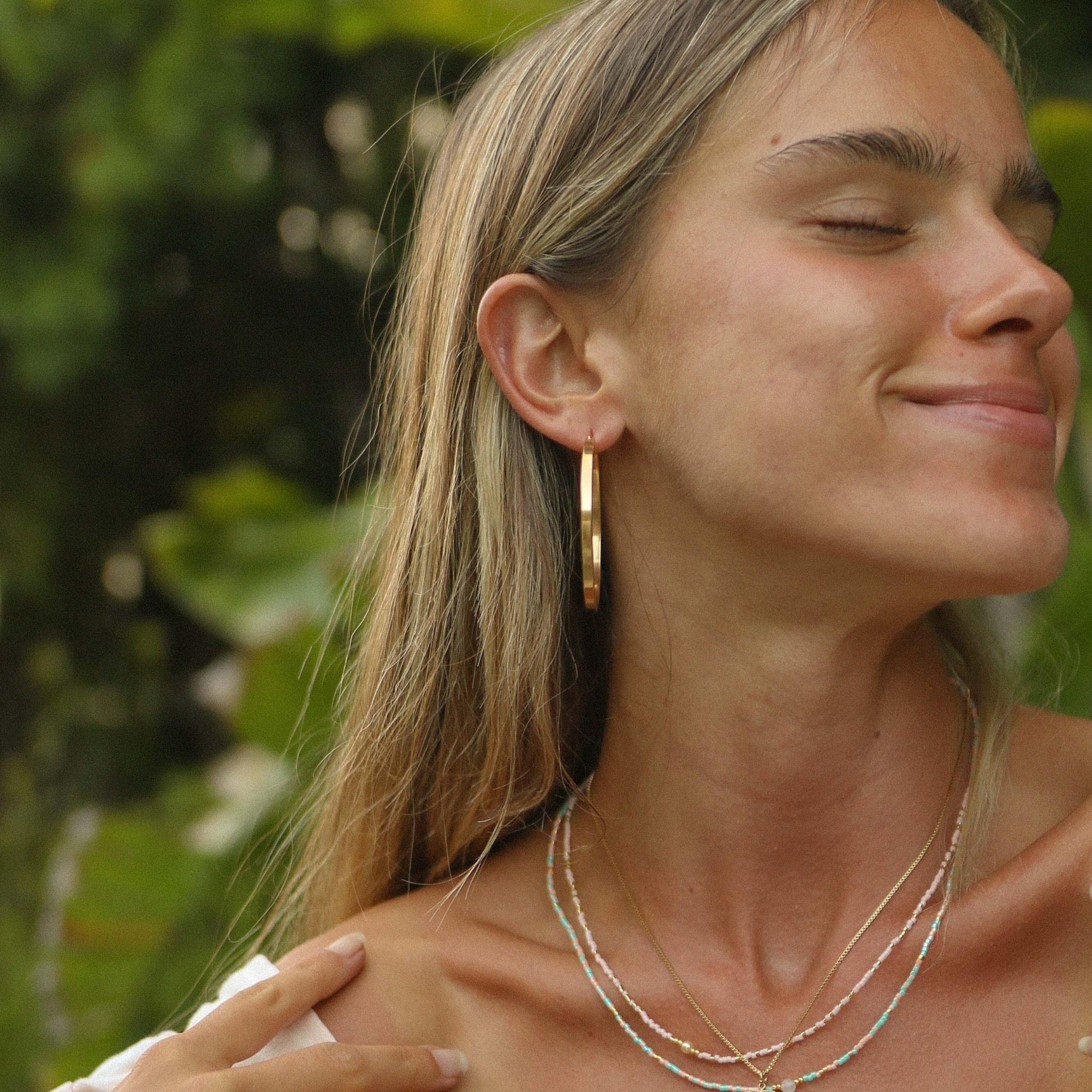 Woman wearing classic polished large gold hoop Earrings in waterproof stainless steel