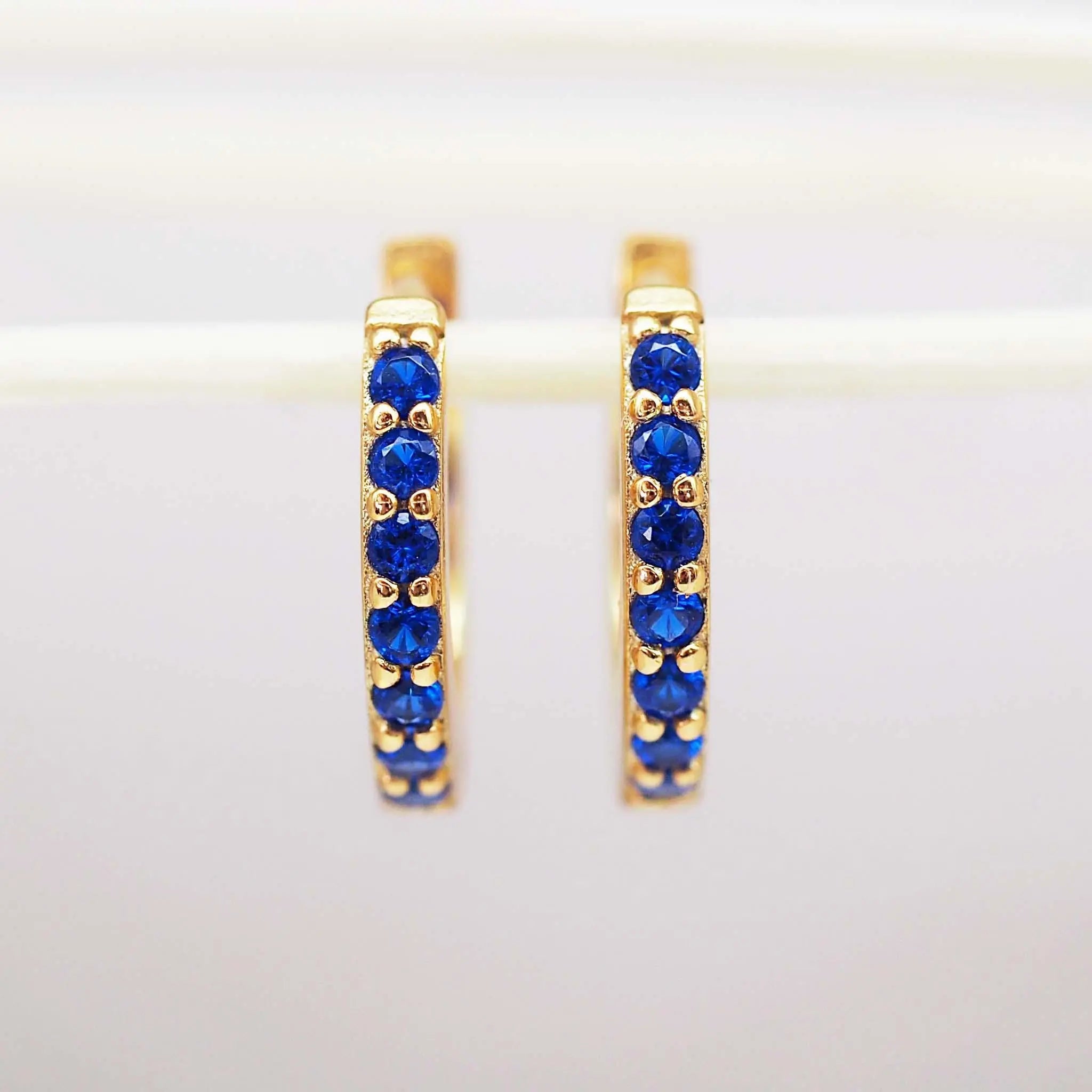 dainty Gold huggie earrings with blue cubic zirconias