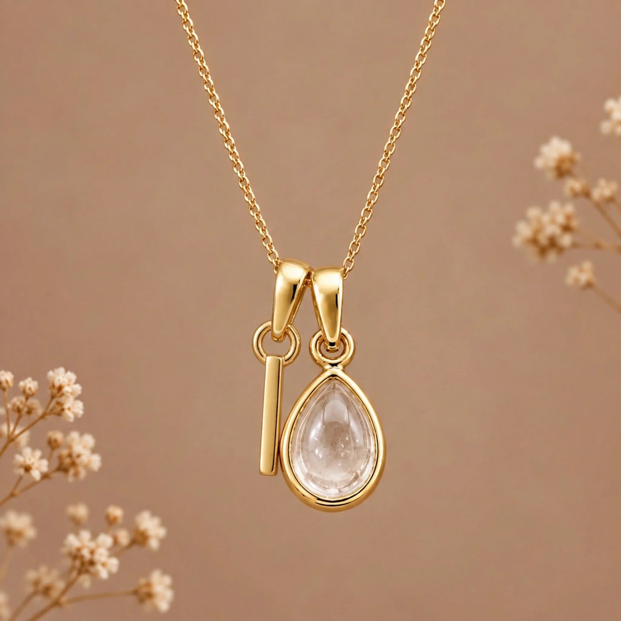 Gold initial I necklace with an April clear quartz teardrop on brown with dried flowers