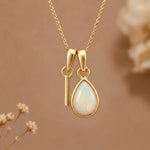 Gold Initial I Pendant and October birthstone Natural Opal Necklace against a warm background
