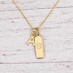 Gold Initial and Cancer Zodiac Necklace with letter A pendant on light wood