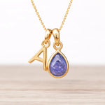 Gold necklace with a teardrop-shaped tanzanite pendant and an 'A' initial.