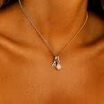 gold initial and april birthstone herkimer Necklace with a gold initial pendant and letter 'A' on a person's neck against a brown background