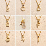 Gold fine chain necklaces with letters A to H on a beige background as personalised Gold Initial Pendant options for April Birthstone Necklace. 
