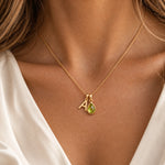 Model wearing a gold initial A and natural August peridot necklace with a soft ivory blouse
