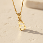 Gold necklace with a 'B' pendant on a beige background