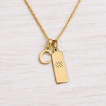 Gold Initial and Aquarius Zodiac Necklace with letter C pendant on light wood