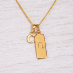Gold Initial and Capricorn Zodiac Necklace with letter C pendant on light wood