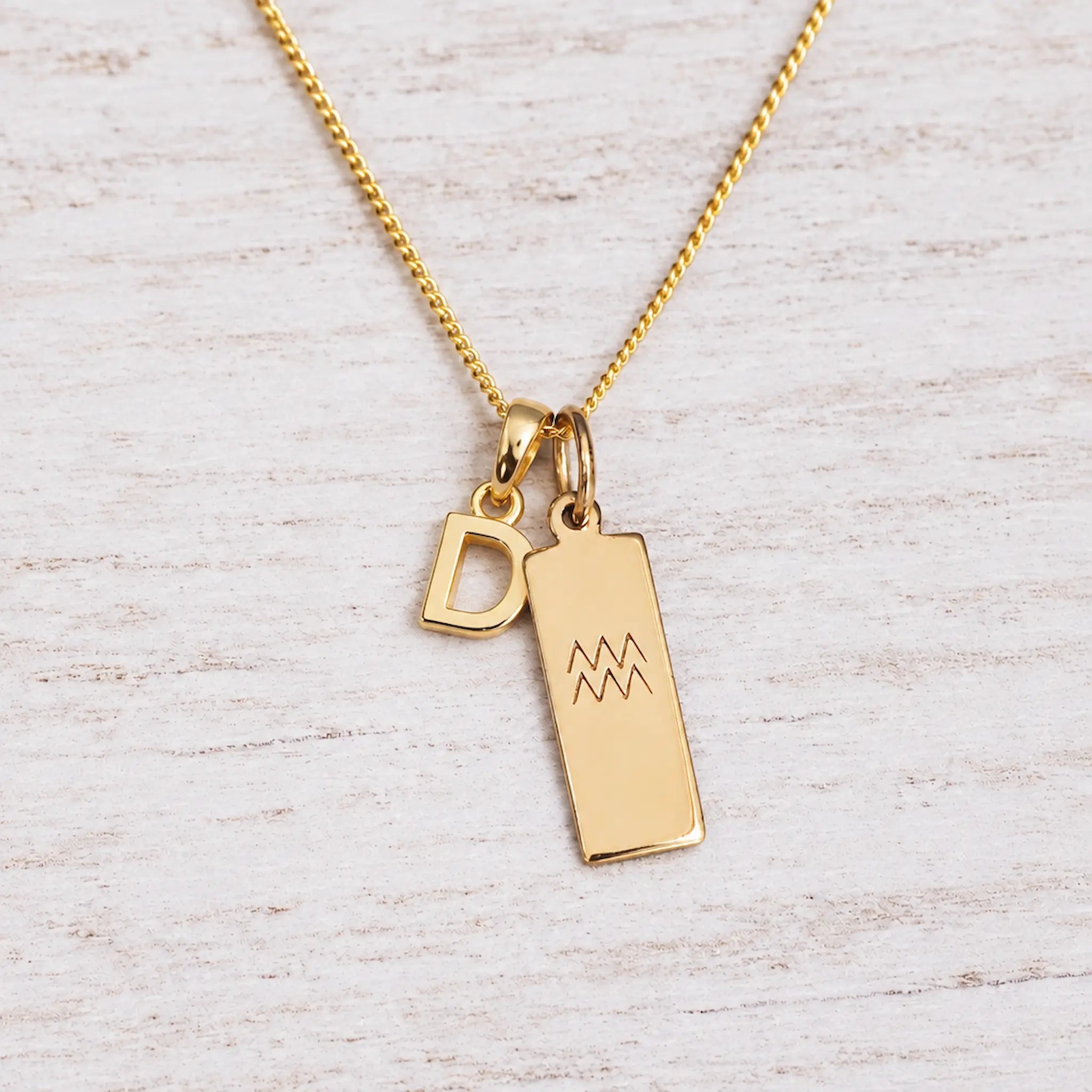 Gold Initial and Aquarius Zodiac Necklace with letter D pendant on light wood