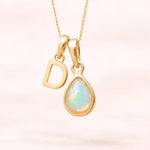 Gold October birthstone necklace with a pear-shaped natural opal pendant and letter 'D' charm with a light background.