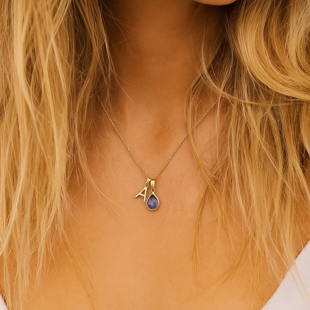 Gold tanzanite necklace with a pendant featuring the letter 'A' worn by a person with blonde hair.