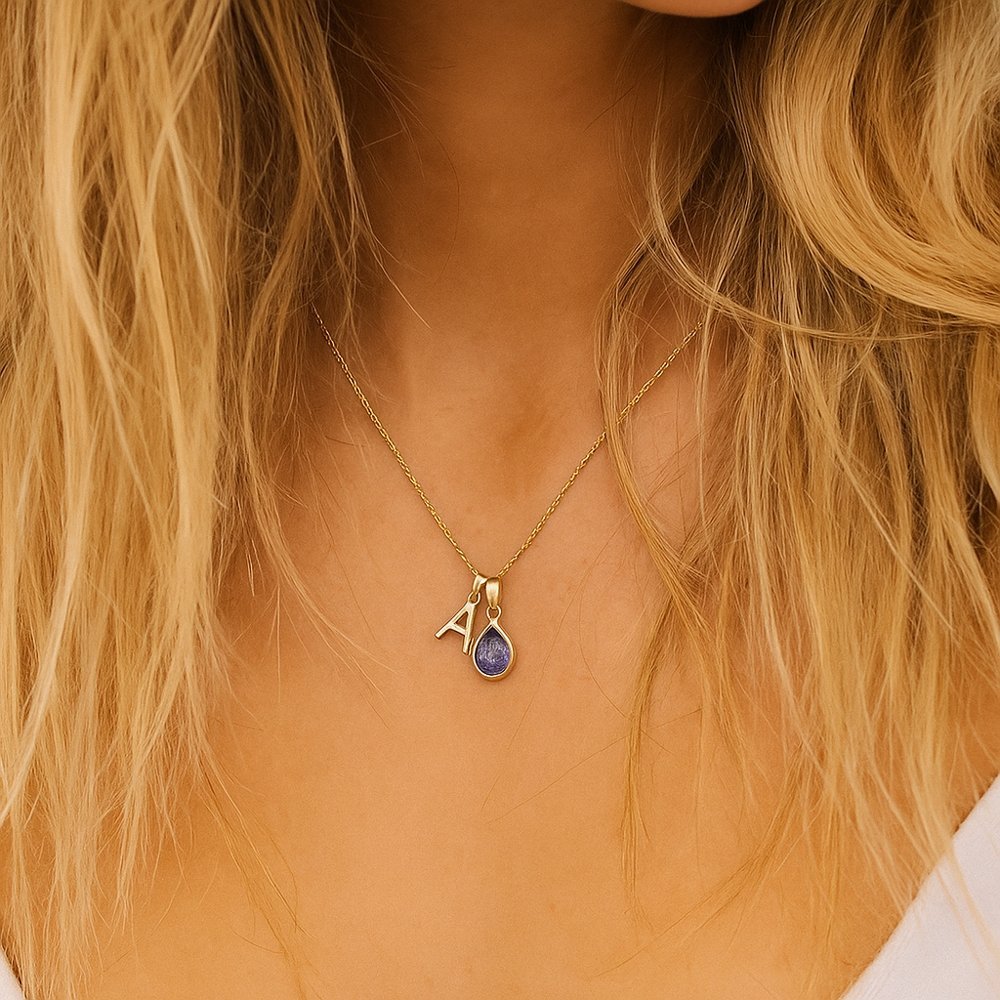 Gold tanzanite necklace with a pendant featuring the letter 'A' worn by a person with blonde hair.