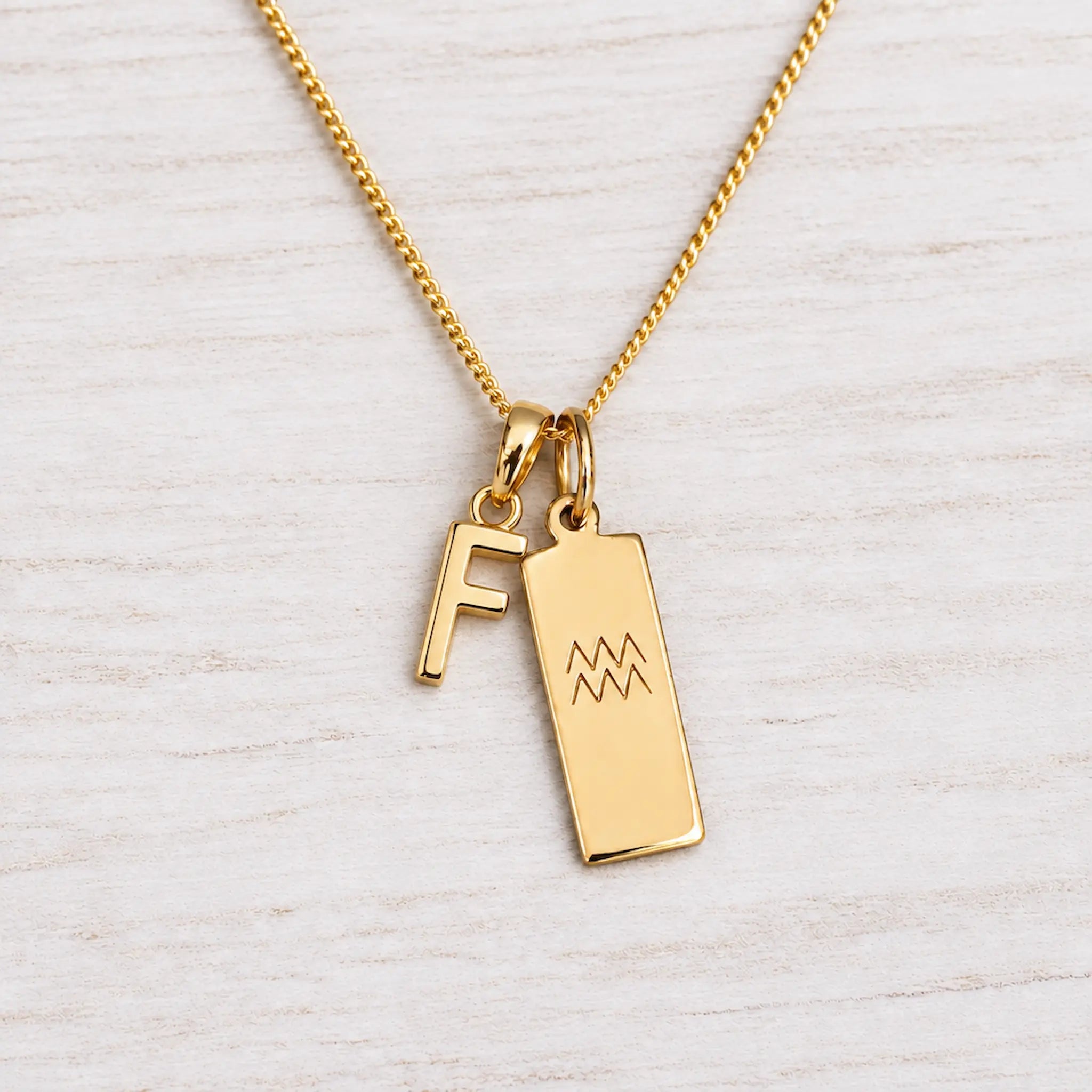 Gold Initial and Aquarius Zodiac Necklace with letter F pendant on light wood