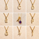 Gold chain necklaces with letter pendants B to H on a beige background, as personalised gold letter options for the Gold February Birthstone Amethyst Necklace.