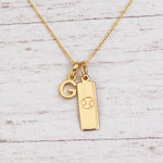 Gold Initial and Cancer Zodiac Necklace with letter G pendant on light wood