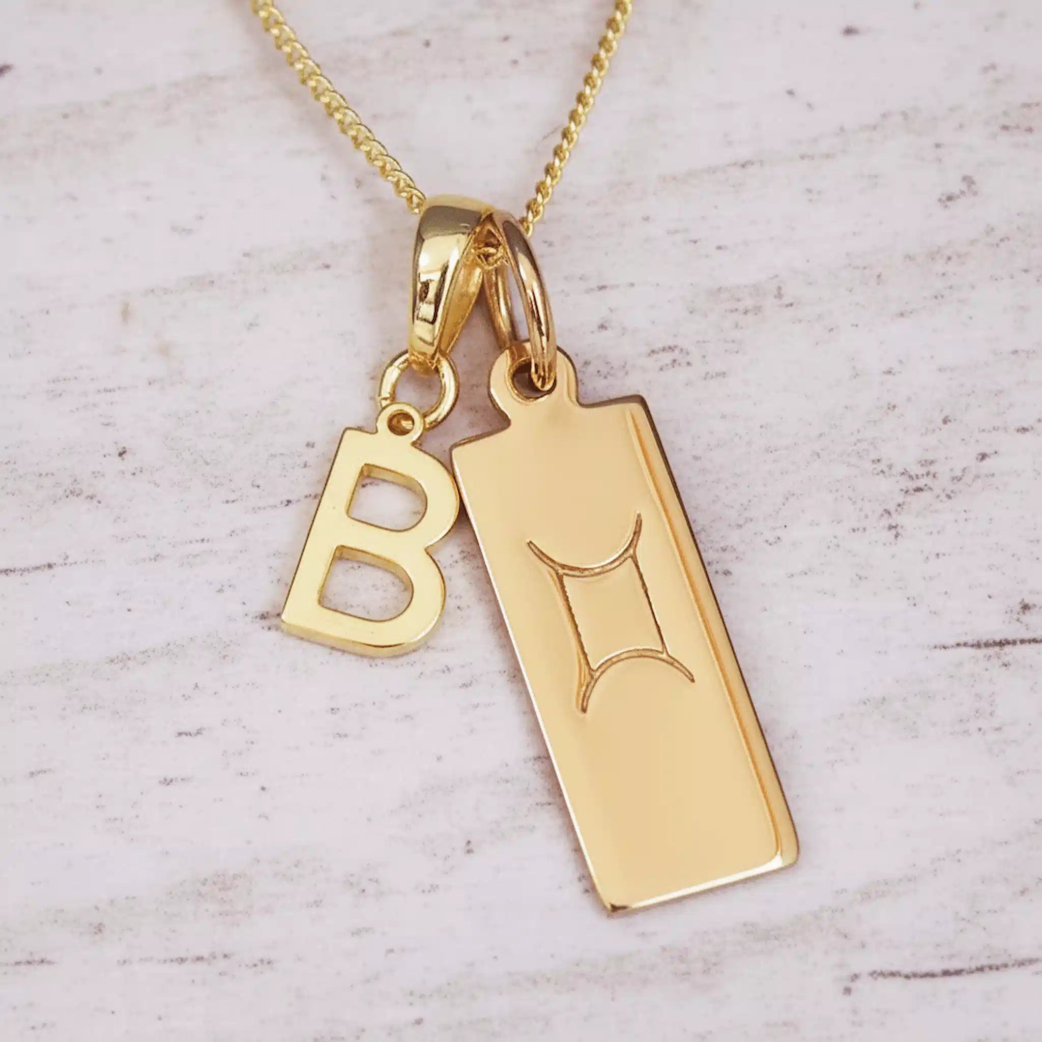 Gold necklace with 'B' pendant on a light wooden background
