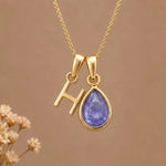 Gold Initial H and December Birthstone natural Tanzanite Necklace on a warm background
