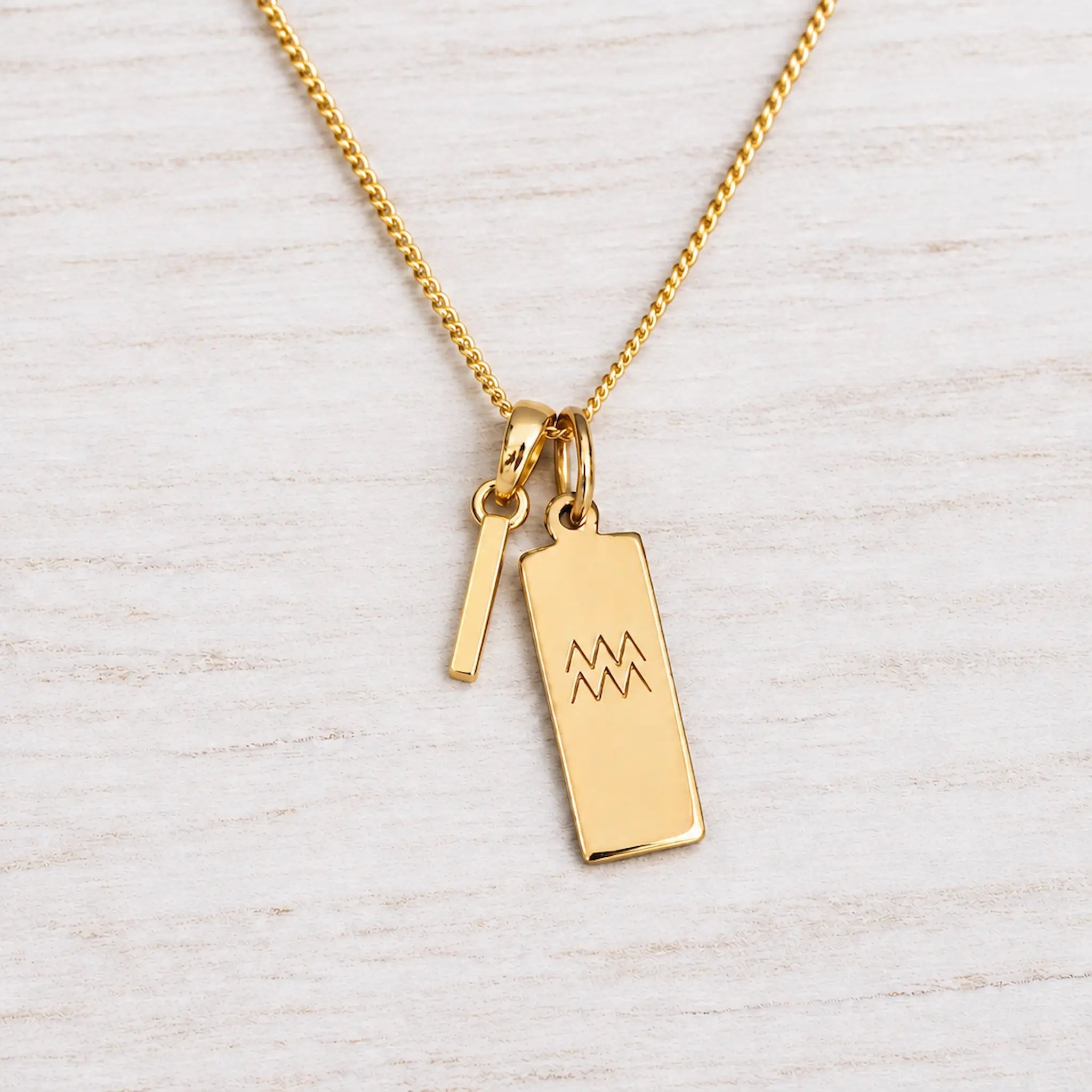 Gold Initial and Aquarius Zodiac Necklace with letter I pendant on light wood