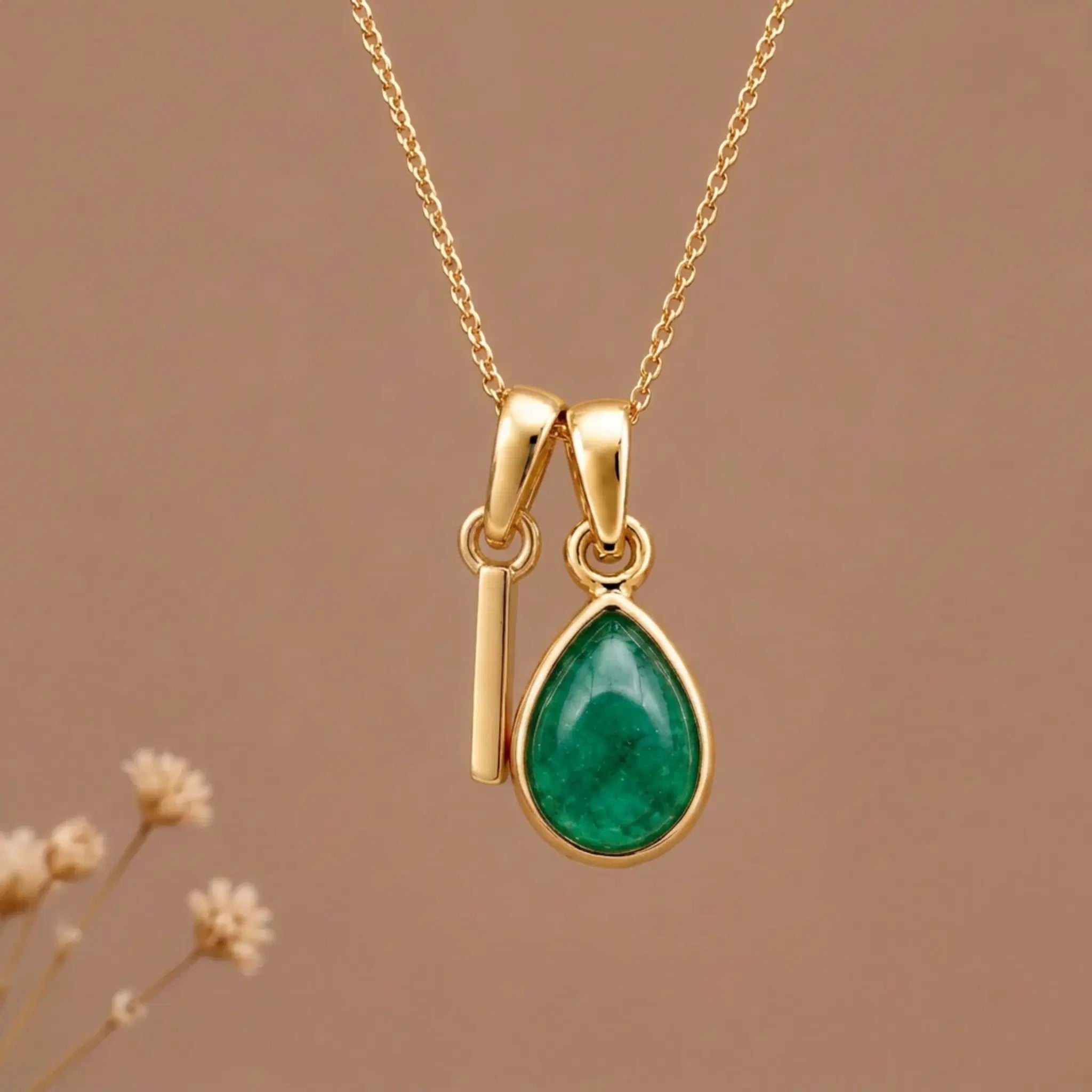 Gold Initial I and May Birthstone Emerald Necklace against a warm background