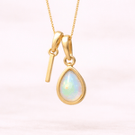 Gold necklace with an 'I' initial charm with a teardrop-shaped opal stone on a white background