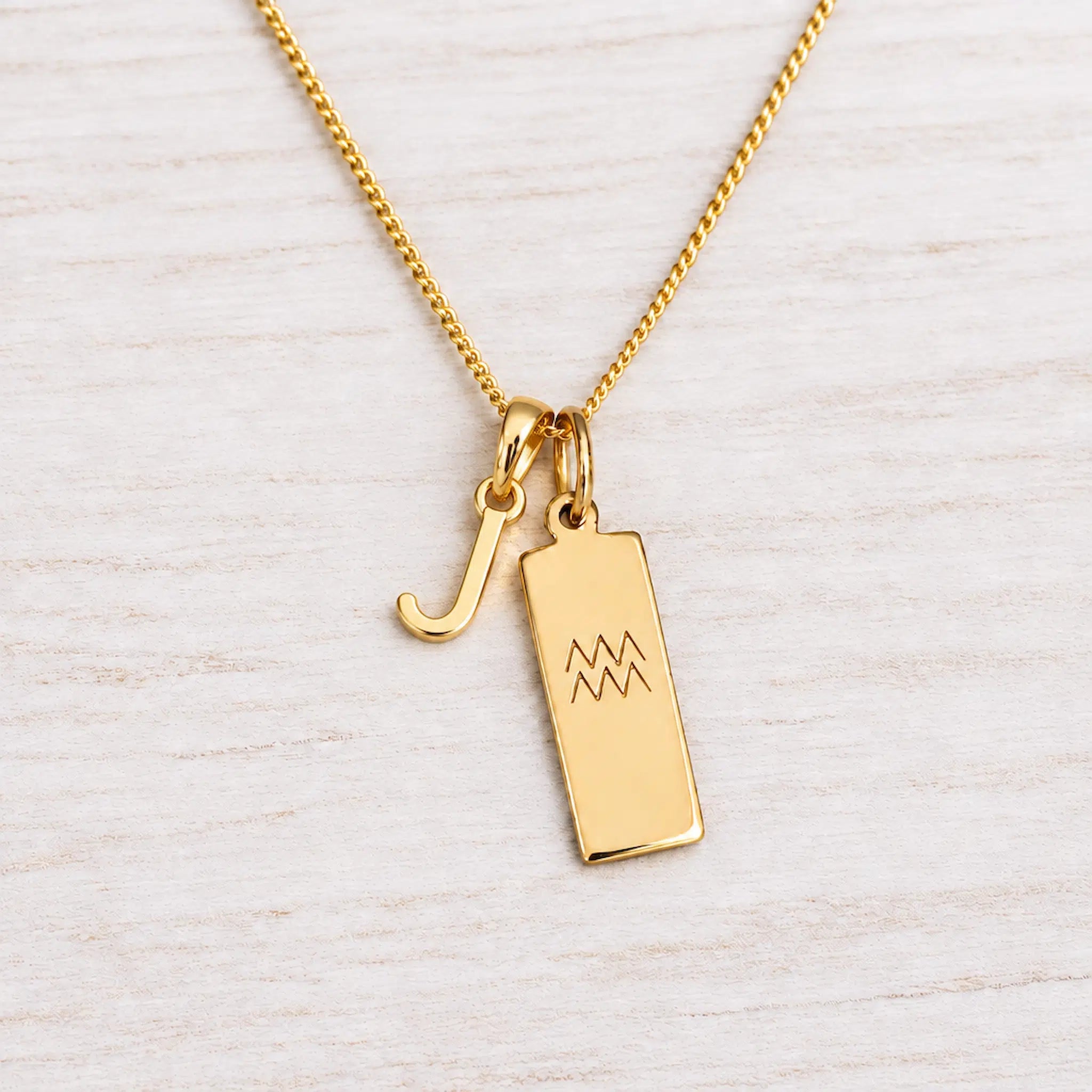 Gold Initial and Aquarius Zodiac Necklace with letter J pendant on light wood